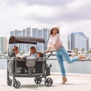 Eine Frau schiebt einen Wonderfold W4 Original Quad 4-Sitzer- Bollerwagen