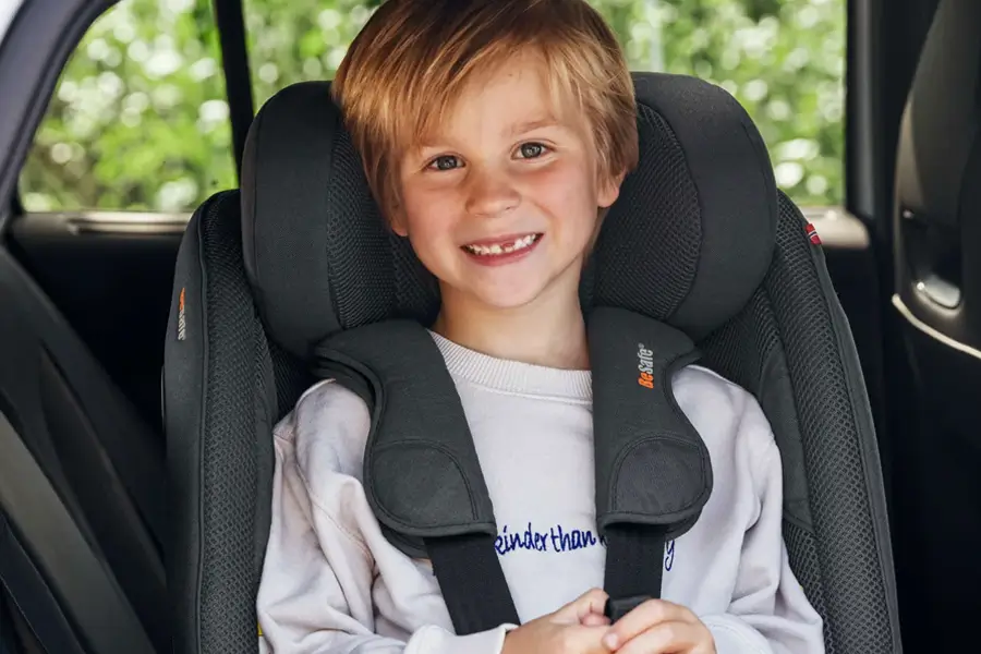 Ein sicher mit dem Sicherheitsgurt gesichertes Kind lächelt im BeSafe Beyond-Autositz und unterstreicht dessen Sicherheits- und Komfortstandard.