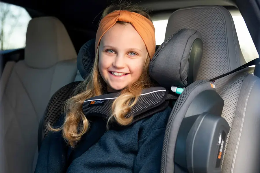 Ein Kind lächelt in die Kamera, während es in der hinteren Reihe auf einem BeSafe Flex FIX 2-Sicherheitssitz sitzt.