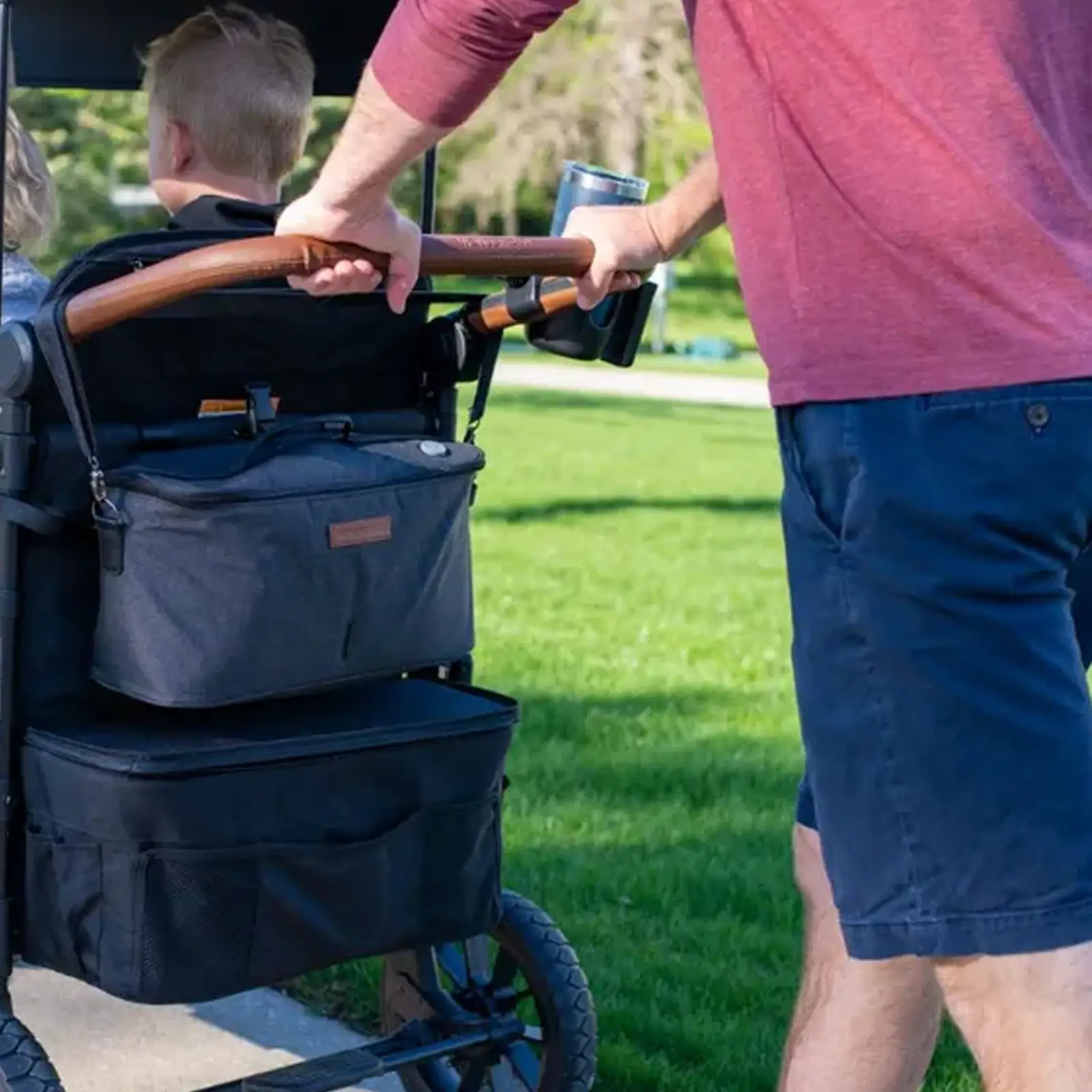 An einem sonnigen Tag schiebt jemand ein Kind mit einer Wonderfold 2-in-1 UV-Licht-Sterilisations- und Kühltasche durch den Park.