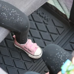 Ein Kind sitzt auf einer Wonderfold Allwetter-Fußmatte mit Strukturmuster.