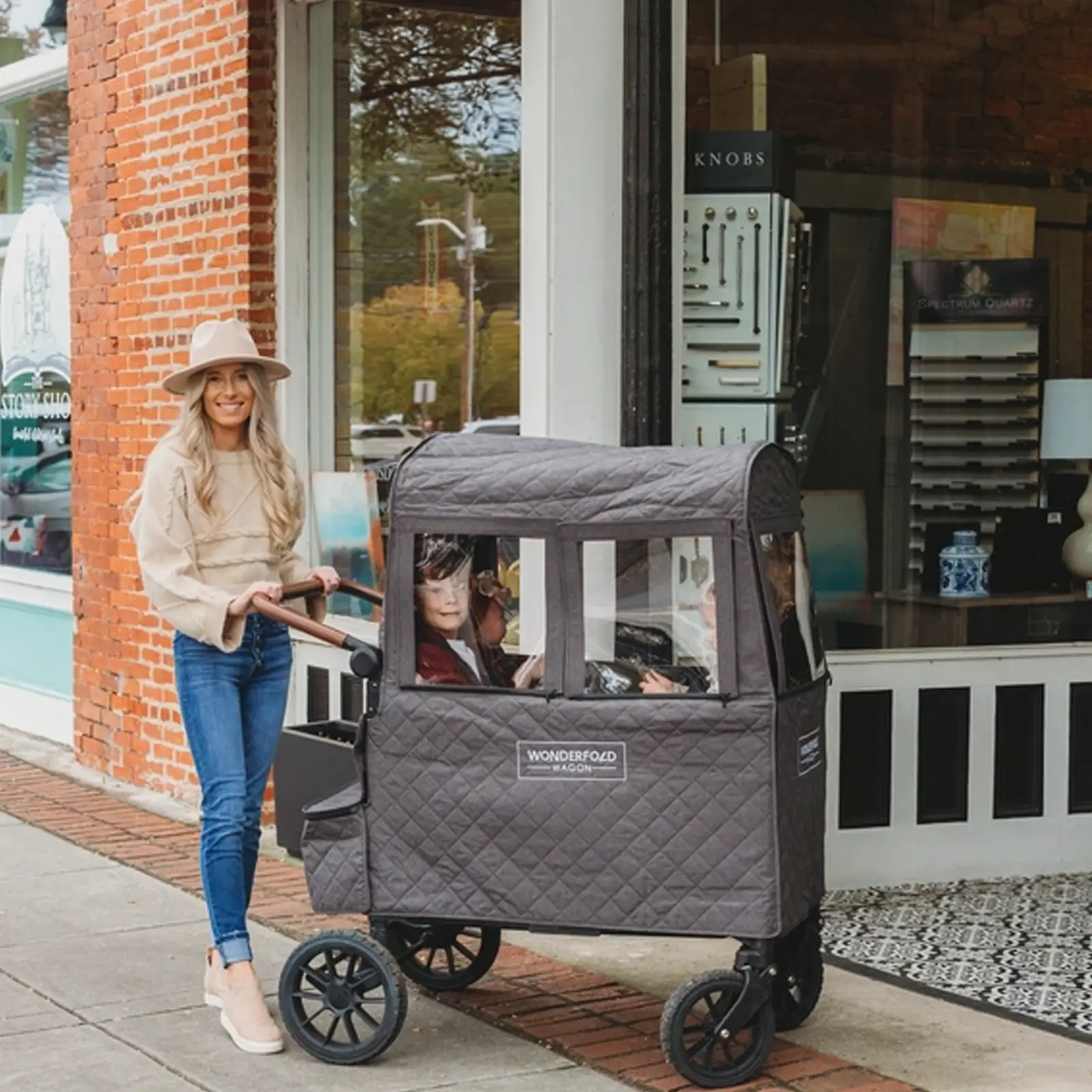 Eine Frau, ausgerüstet mit einem Wonderfold Cold Weather Shield für W2 2.0, schiebt zwei Kinder.