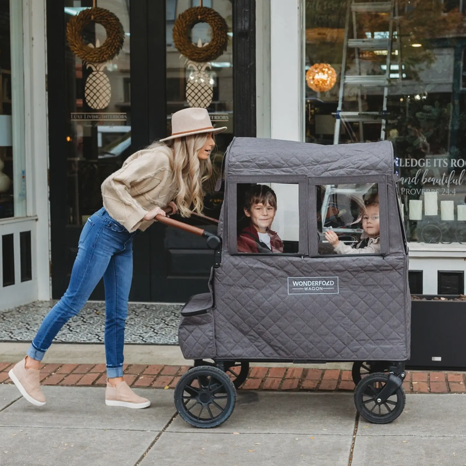 Eine Frau schiebt zwei Kinder in einem großen Wonderfold-Kinderwagen mit Wonderfold Cold Weather Shield