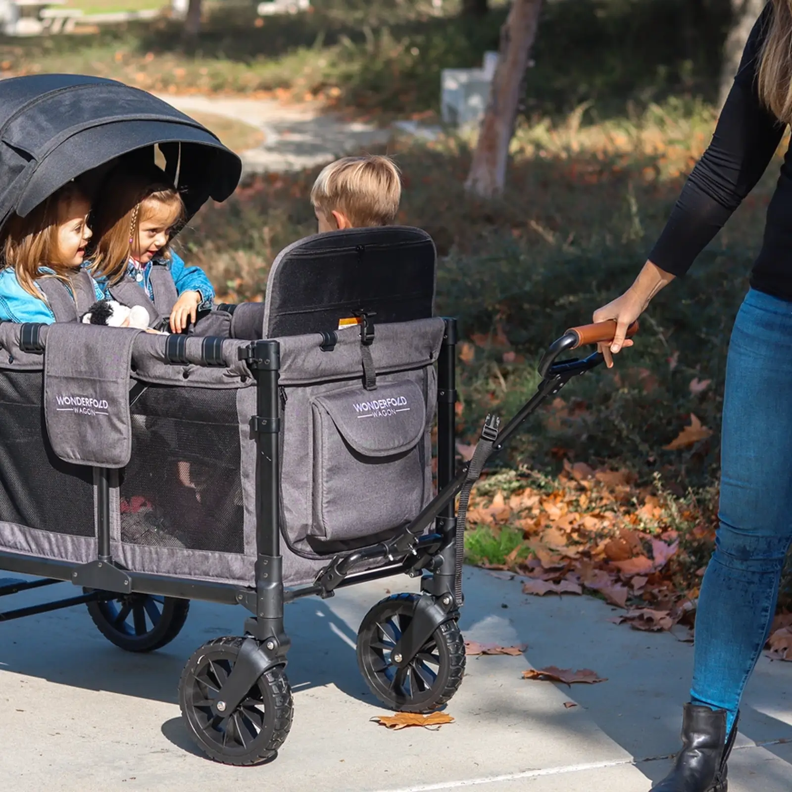 In einem Park zieht jemand einen Kinderwagen mit dem Wonderfold Ziehgriff W-Serie (kompatibel mit allen Wagen der W-Serie)